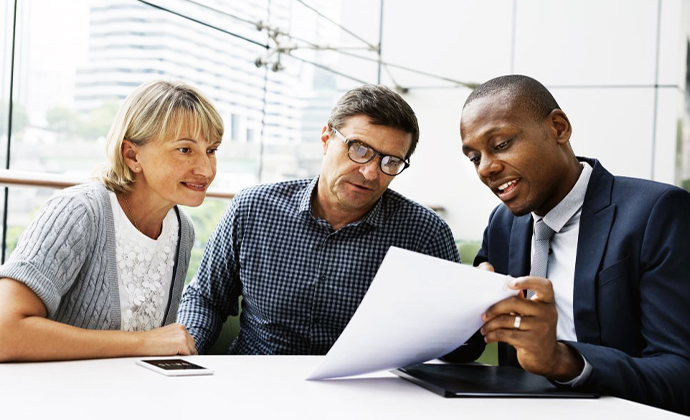 Couple looking over mortgage paperwork with lender photo